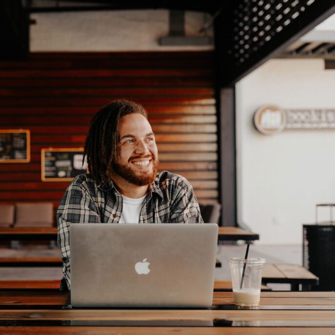 a man with a laptop smiling off into the distance